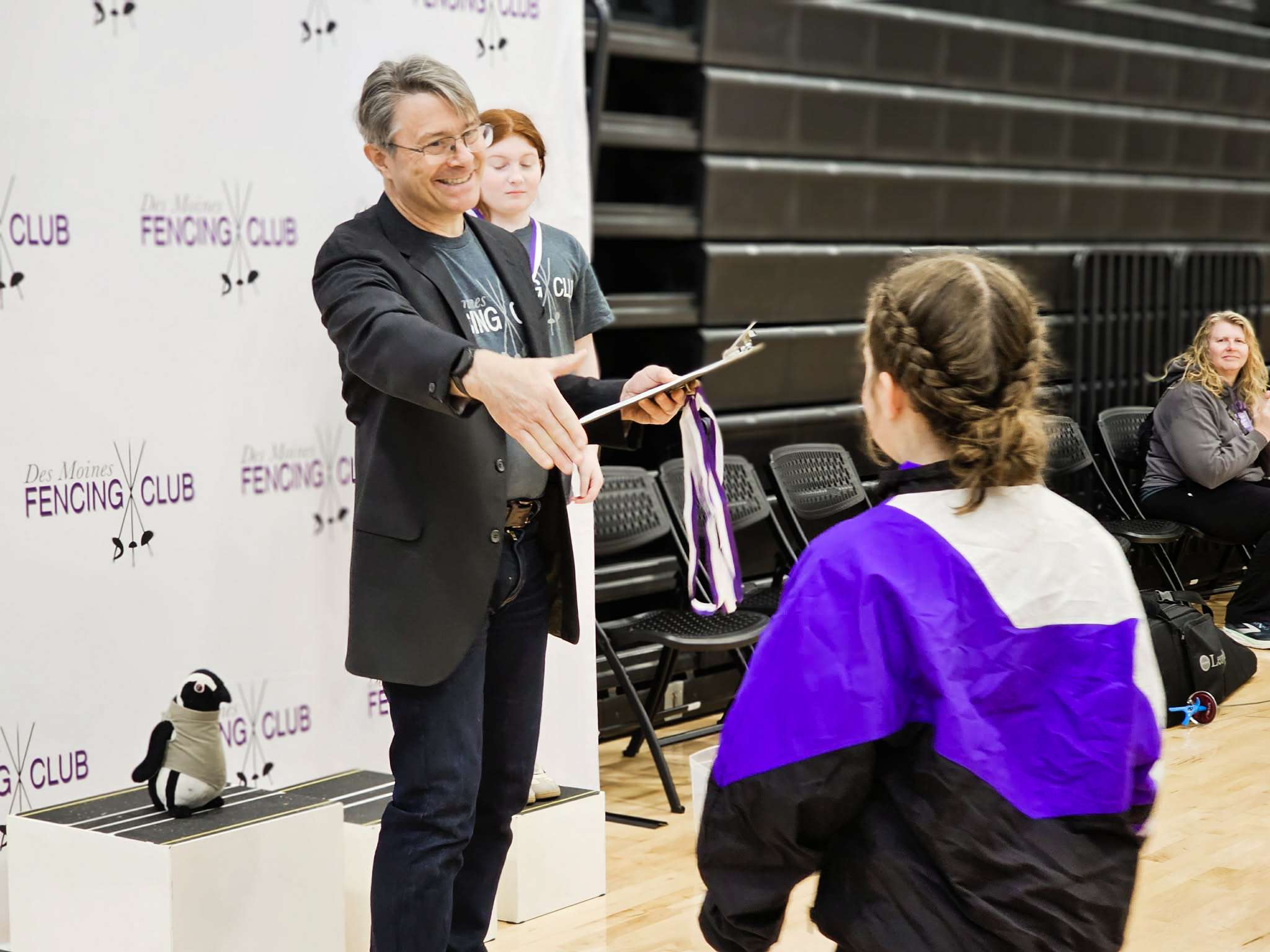 A club fencer receiving a tournament medal